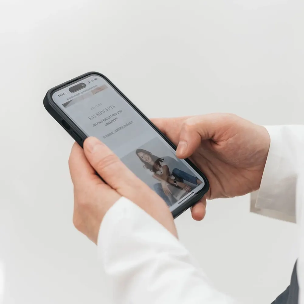Hands holding a phone showing the KAS KONCEPTS website