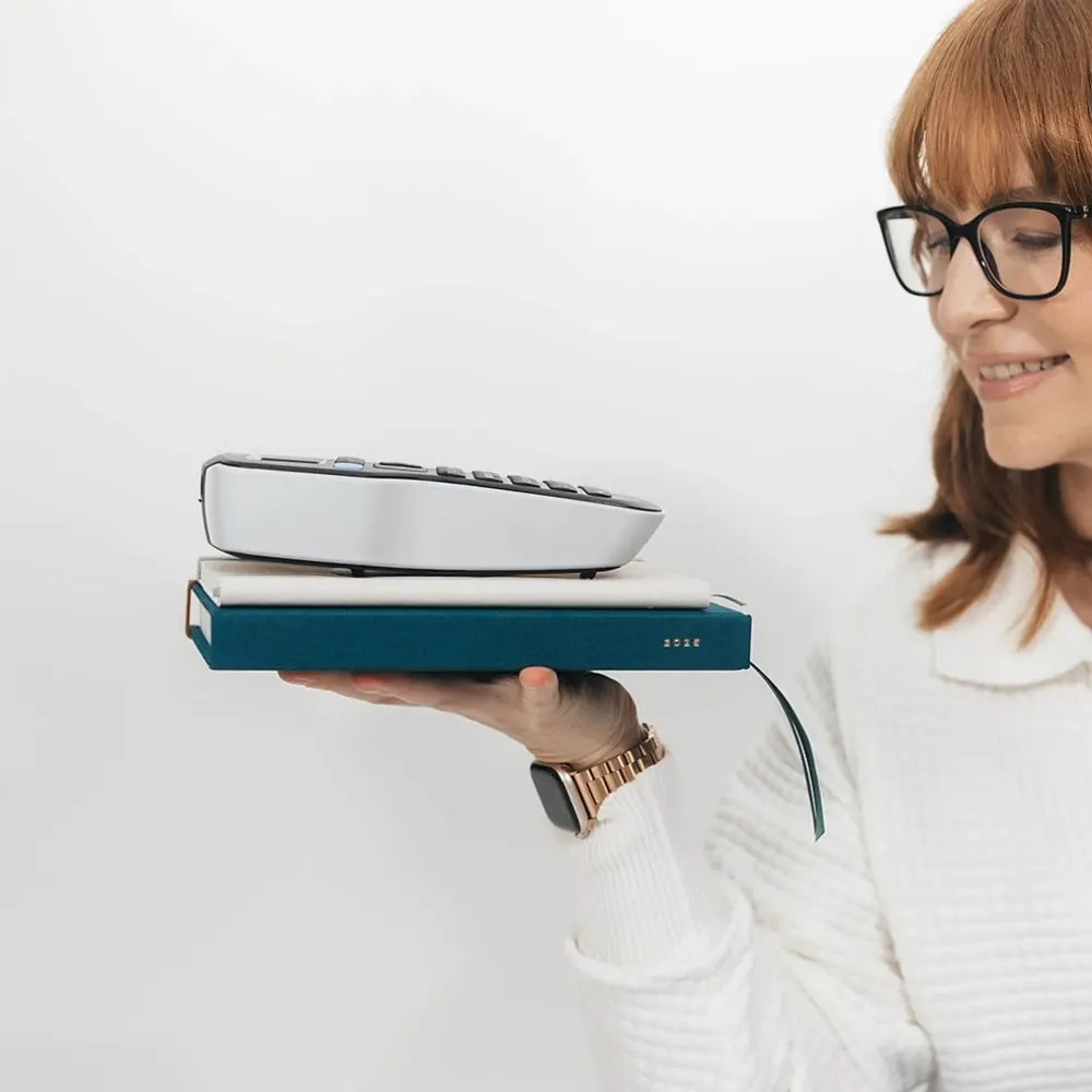 Kristen smiling while balancing a label maker on a teal planner